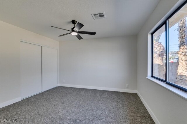 carpeted spare room featuring ceiling fan and a wealth of natural light