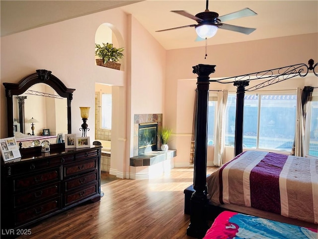 bedroom featuring ceiling fan, hardwood / wood-style flooring, lofted ceiling, and a fireplace