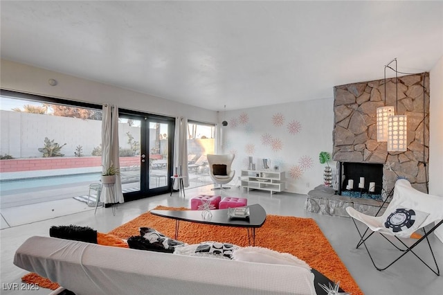 living room with concrete flooring, a fireplace, and french doors