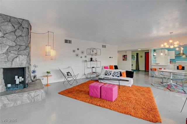 living room featuring concrete floors, a chandelier, and a stone fireplace