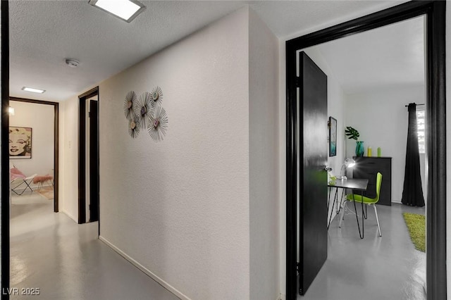 hall with a textured ceiling and concrete floors