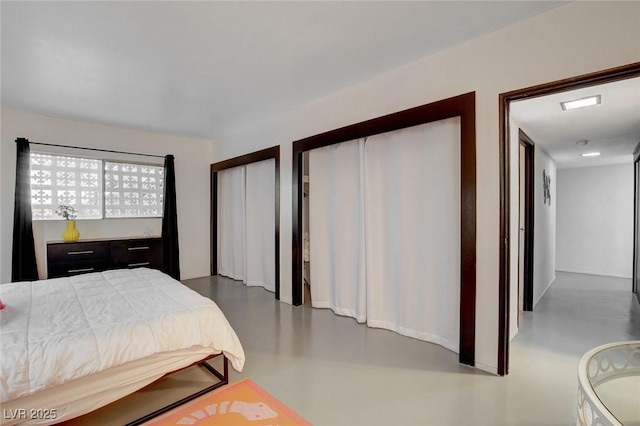 bedroom with concrete floors and multiple closets