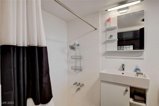 bathroom featuring shower / bath combo with shower curtain, a textured ceiling, and vanity