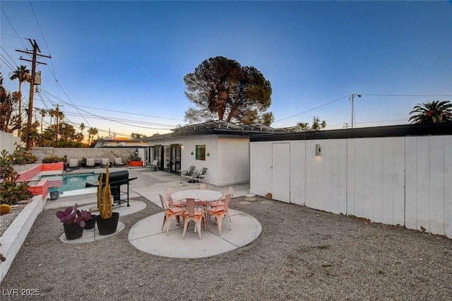 back of house with a fenced in pool, a patio area, and a storage unit