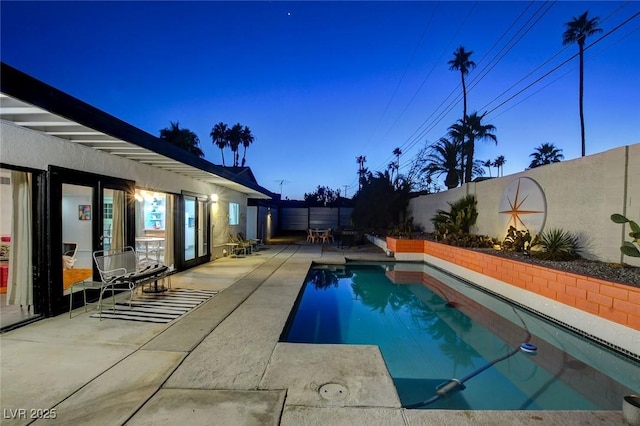 pool at dusk with a patio area