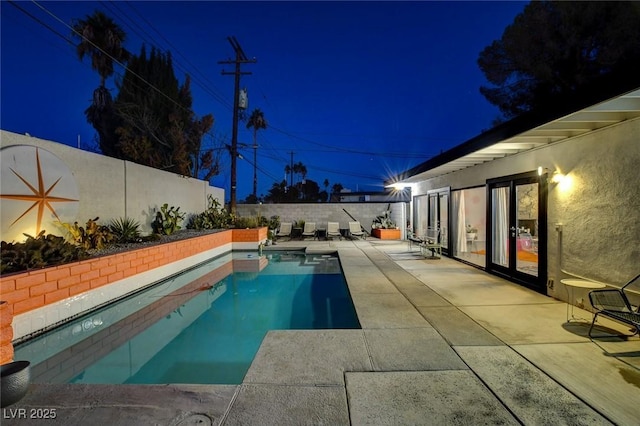 pool at twilight featuring a patio area