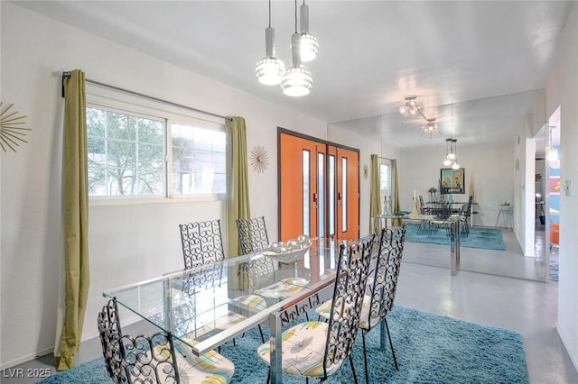 dining area featuring concrete flooring and a notable chandelier