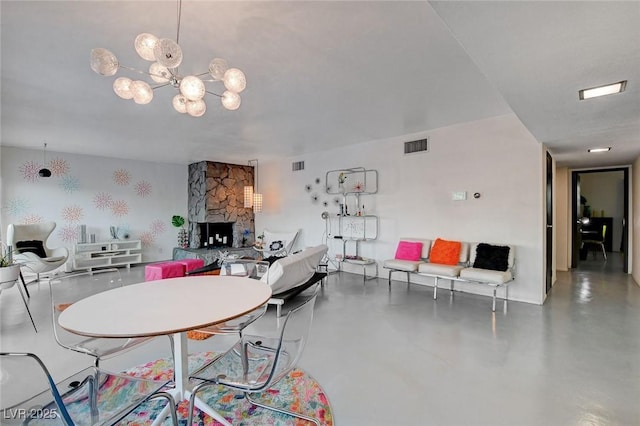 dining area with concrete flooring, a notable chandelier, and a fireplace