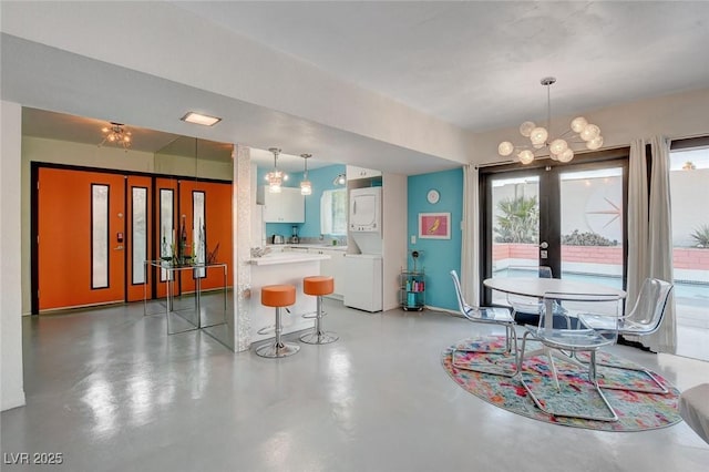 dining room featuring french doors, a notable chandelier, and concrete flooring