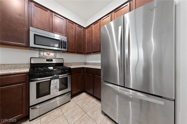 kitchen with light tile patterned floors, stainless steel appliances, and dark brown cabinets