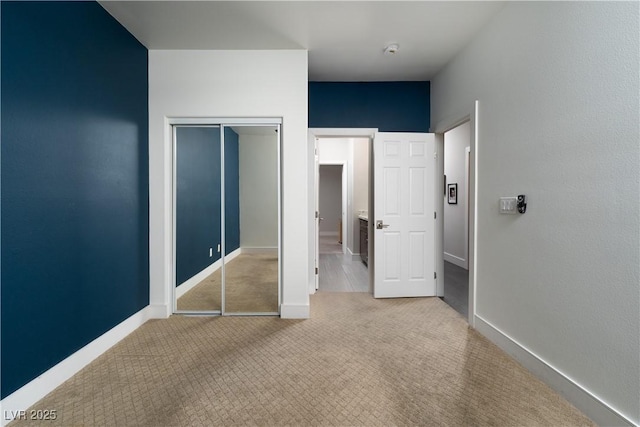 unfurnished bedroom with a closet and light colored carpet