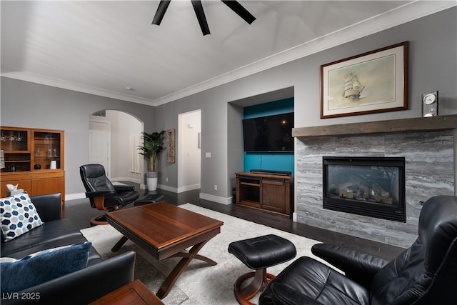 living room with ceiling fan, wood-type flooring, a fireplace, and ornamental molding