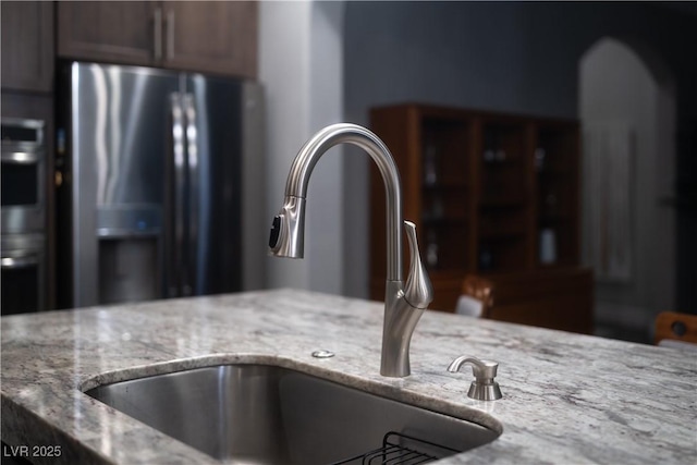 room details with stainless steel fridge, sink, and light stone counters