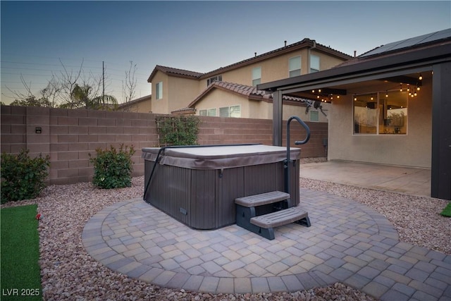 patio terrace at dusk featuring a hot tub