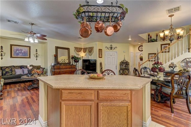 kitchen featuring decorative light fixtures, a center island, wood-type flooring, light brown cabinets, and ceiling fan with notable chandelier