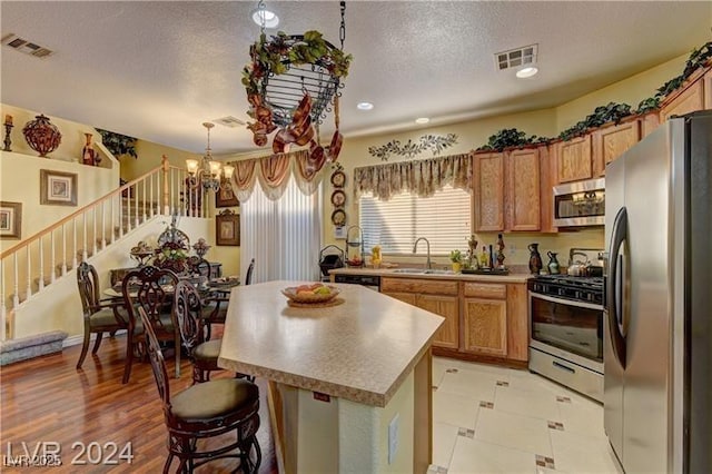 kitchen featuring an inviting chandelier, a breakfast bar area, stainless steel appliances, a kitchen island, and sink