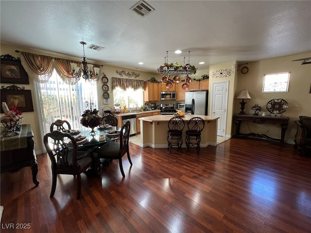 dining area with sink, plenty of natural light, dark wood-type flooring, and an inviting chandelier