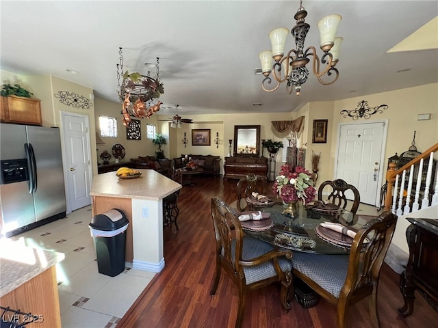 dining space featuring ceiling fan with notable chandelier and dark wood-type flooring