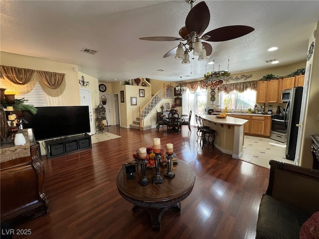 living room featuring sink, hardwood / wood-style floors, a textured ceiling, and ceiling fan