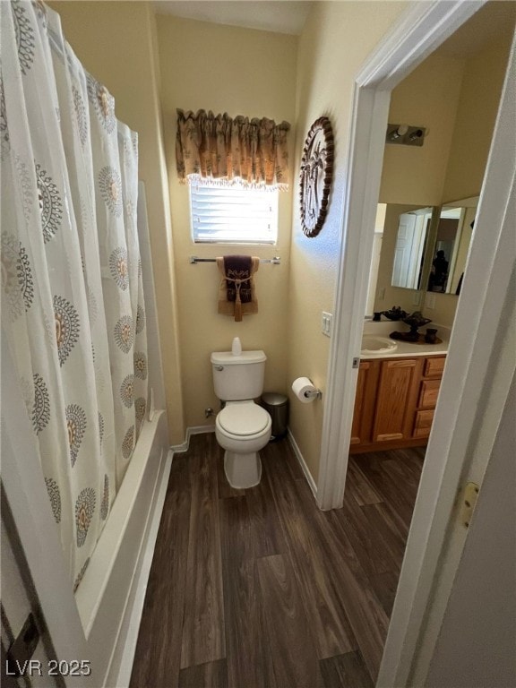 full bathroom featuring wood-type flooring, shower / bath combo with shower curtain, toilet, and vanity