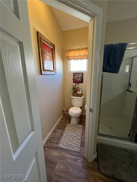 bathroom featuring hardwood / wood-style floors, a shower with door, and toilet