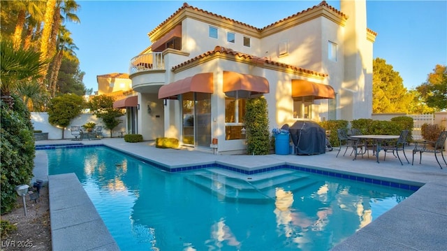 back of property with a patio, a balcony, and a fenced in pool