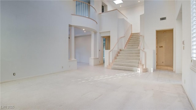 interior space with decorative columns, a high ceiling, and light carpet