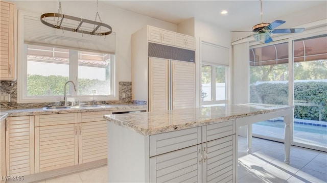 kitchen featuring sink, backsplash, light tile patterned floors, and a center island