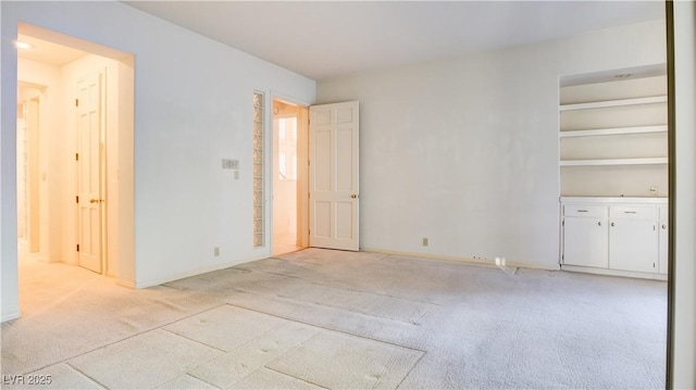 spare room featuring light carpet and built in features