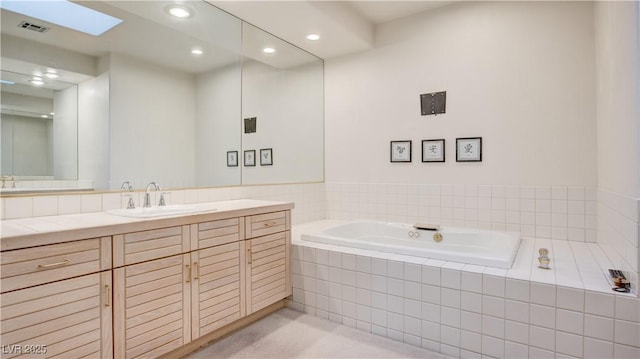 bathroom with tiled bath, vanity, and a skylight