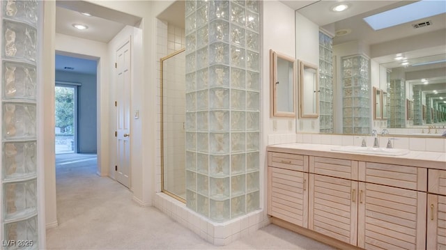 bathroom with a skylight, a tile shower, and vanity