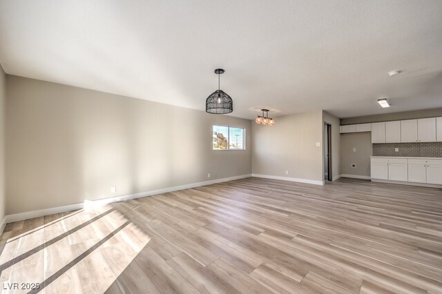 unfurnished living room with a notable chandelier and light hardwood / wood-style floors