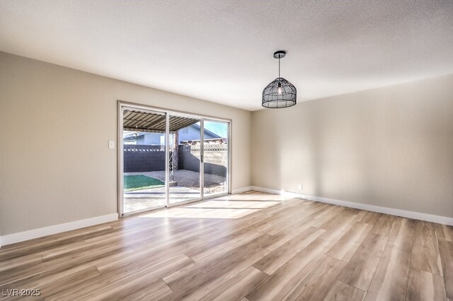 unfurnished room with a textured ceiling and light hardwood / wood-style floors