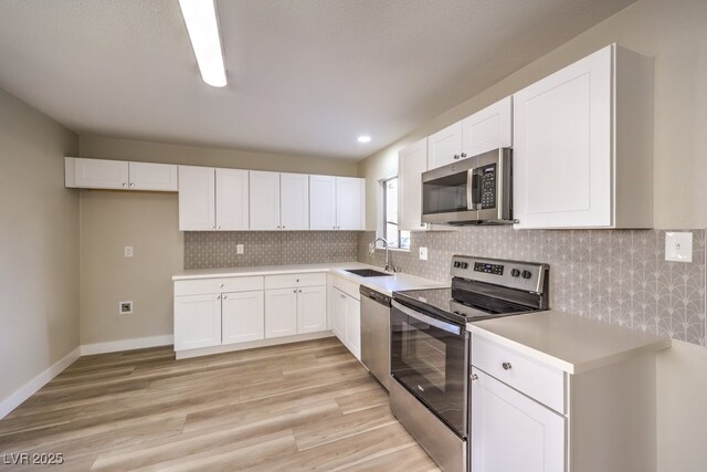 kitchen with tasteful backsplash, light hardwood / wood-style floors, sink, white cabinetry, and appliances with stainless steel finishes