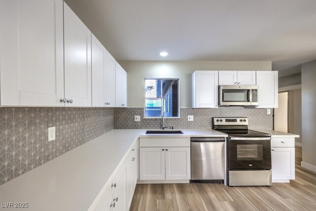 kitchen with light hardwood / wood-style floors, sink, white cabinets, and stainless steel appliances