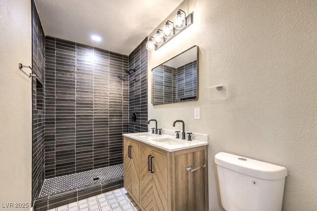 bathroom with toilet, tiled shower, tile patterned floors, a textured ceiling, and vanity