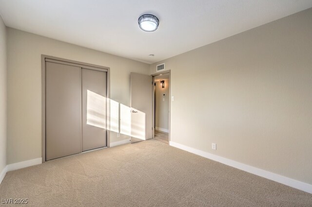 unfurnished bedroom featuring light carpet and a closet