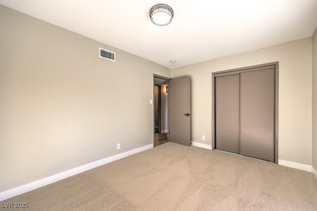 unfurnished bedroom with a closet and light carpet