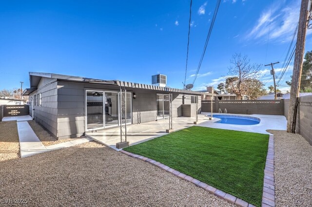 rear view of property with a lawn, central air condition unit, a patio area, and a fenced in pool