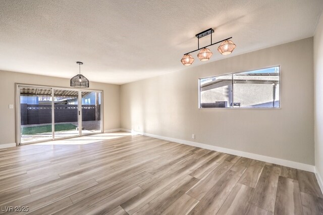 unfurnished dining area with a textured ceiling and light hardwood / wood-style flooring