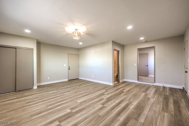 unfurnished bedroom featuring connected bathroom and light wood-type flooring