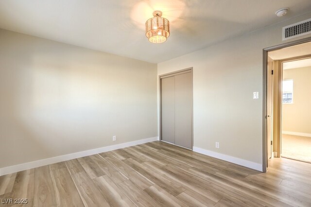 unfurnished bedroom with light wood-type flooring and a closet