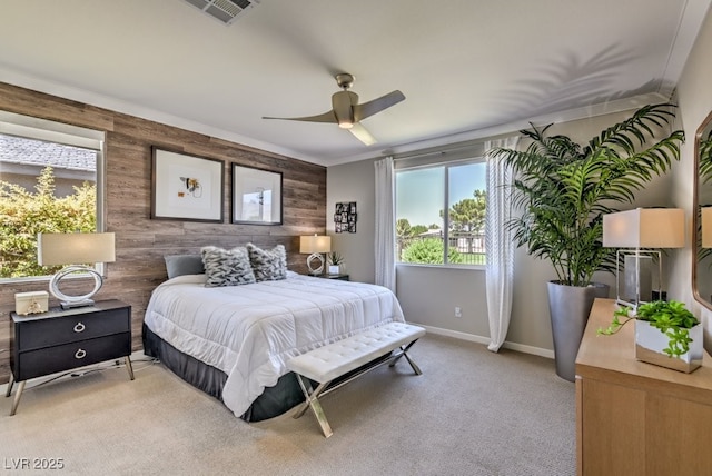 bedroom with ceiling fan, light colored carpet, wooden walls, and ornamental molding