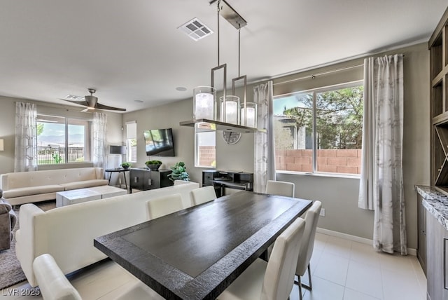 dining room with ceiling fan, light tile patterned flooring, a healthy amount of sunlight, and a fireplace