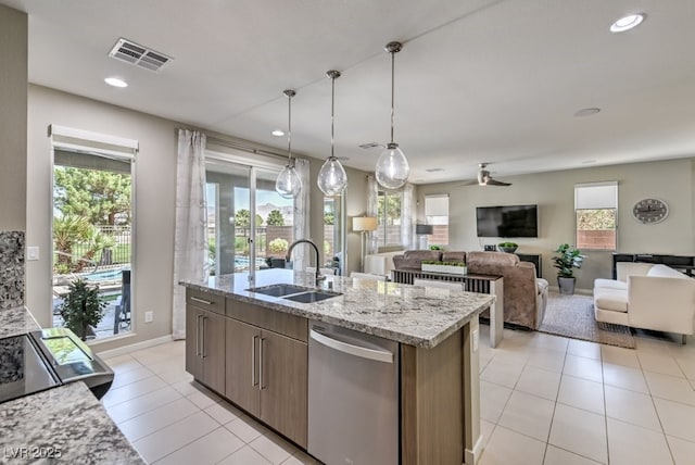 kitchen with a center island with sink, hanging light fixtures, light stone countertops, stainless steel dishwasher, and sink