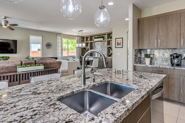 kitchen with decorative backsplash, light tile patterned flooring, dishwasher, light stone counters, and sink