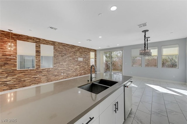 kitchen featuring decorative light fixtures, stainless steel dishwasher, white cabinets, and sink