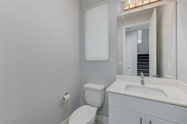 bathroom with toilet, baseboards, and vanity