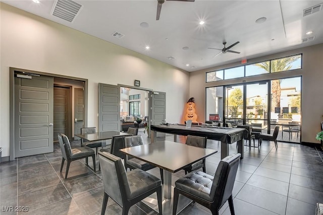 dining space with a high ceiling, visible vents, and a ceiling fan