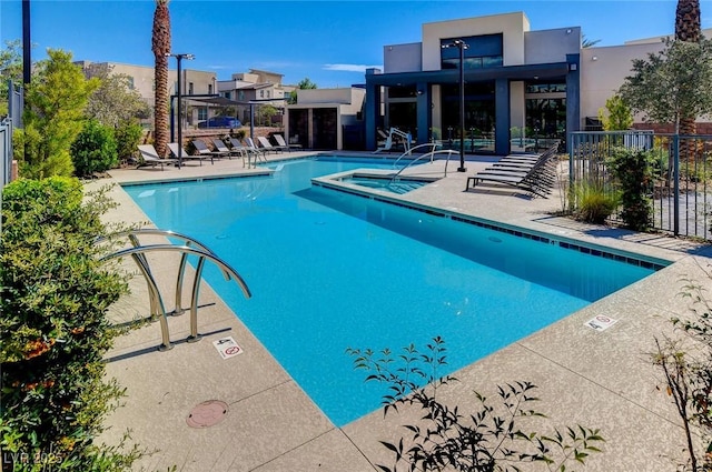 pool featuring a patio area, a hot tub, and fence